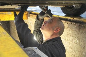 MOT inspecting the underside of a car
