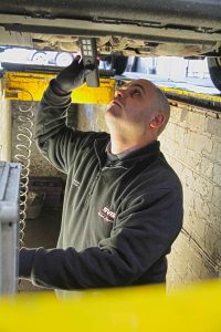 MOT inspecting the underside of a car